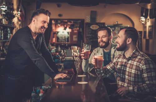 two men cheersing and exchanging irish blessings with male bartender at a local pub