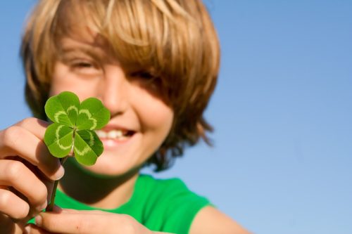 young boy holding a four leaf clover