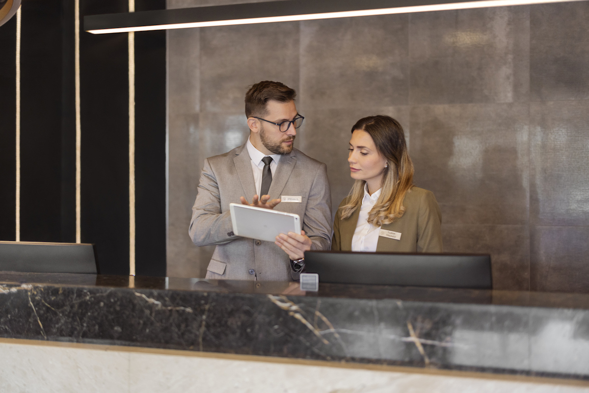 Male and female hotel receptionists using digital tablet while working at counter