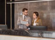 Male and female hotel receptionists using digital tablet while working at counter
