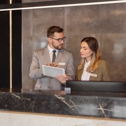 Male and female hotel receptionists using digital tablet while working at counter