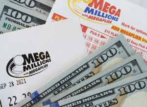 A close up of Mega Millions lottery tickets and $100 bills