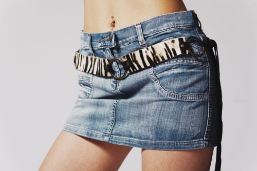 Close up of a woman fit hips in jeans mini skirt. Studio shot