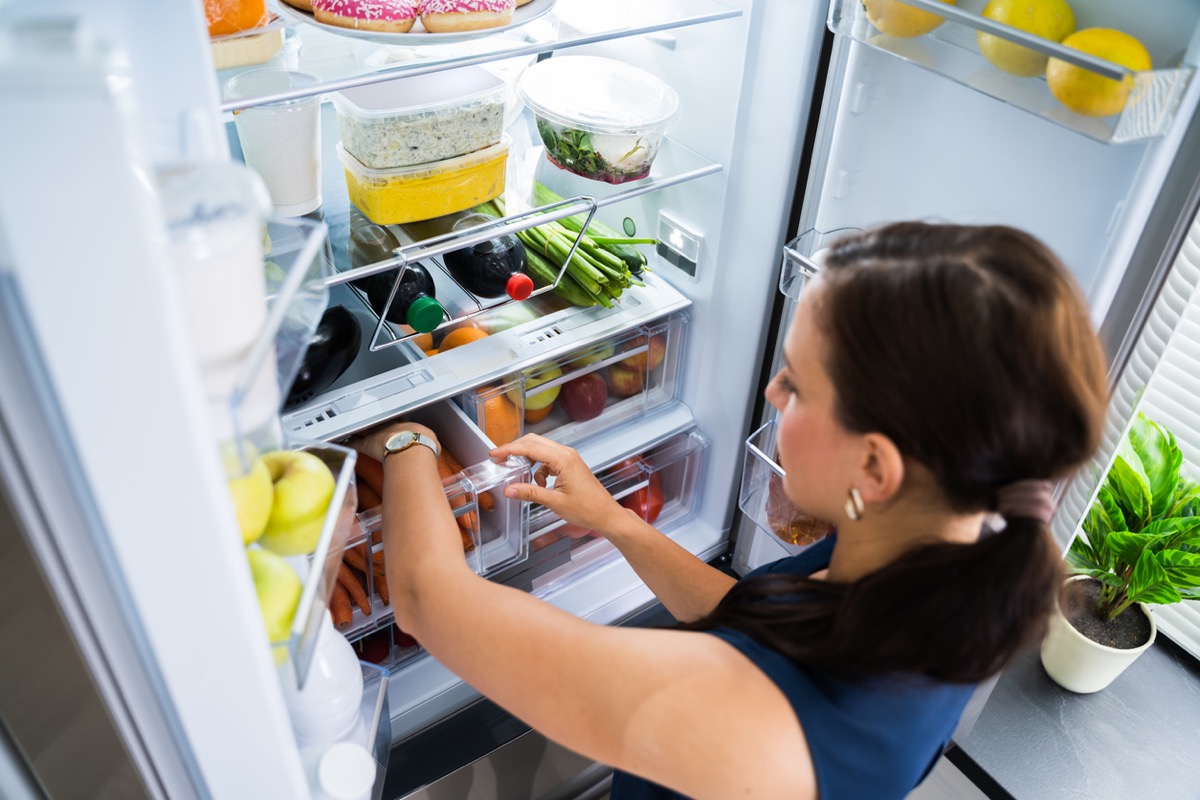 Women Looking For Food Inside Fridge In Kitchen