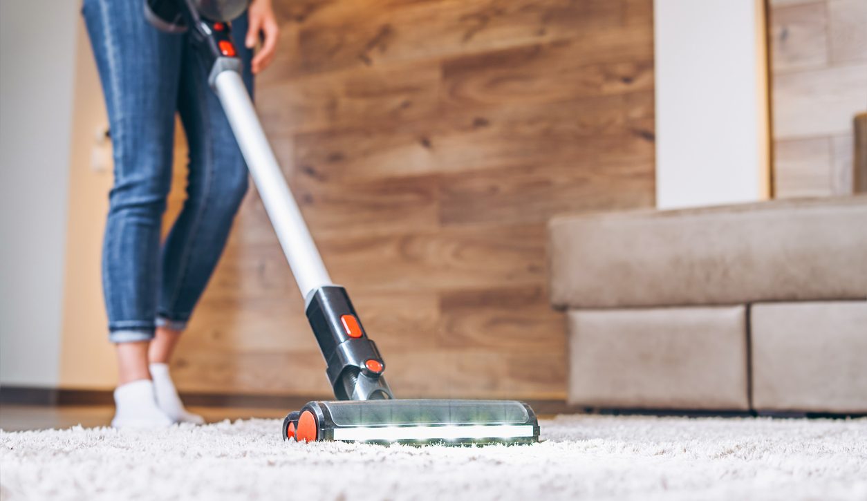 A close up of a person vacuuming a carpet