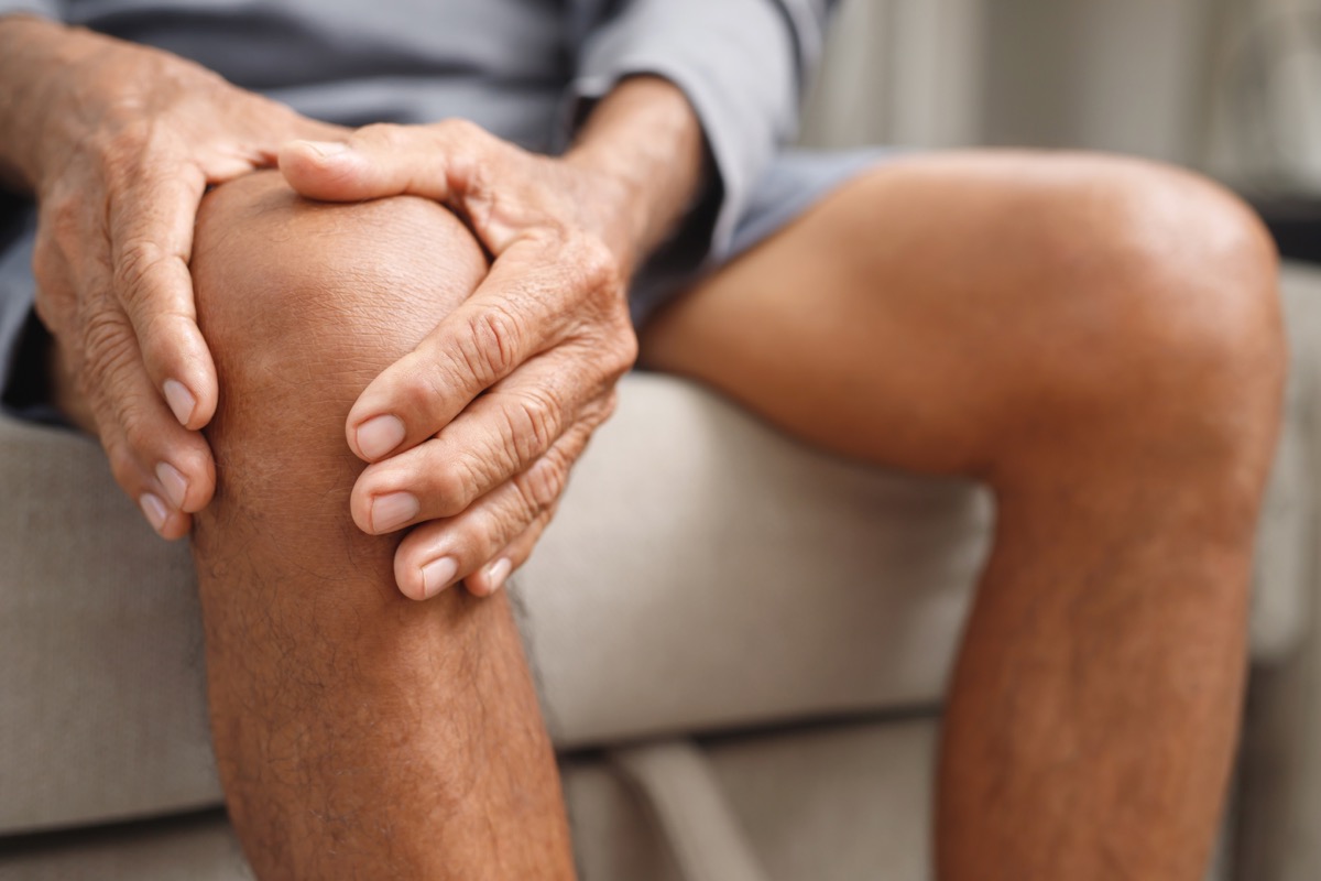 man with inflammation holding knee