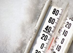 A close up of a thermometer resting in snow reading a low temperature