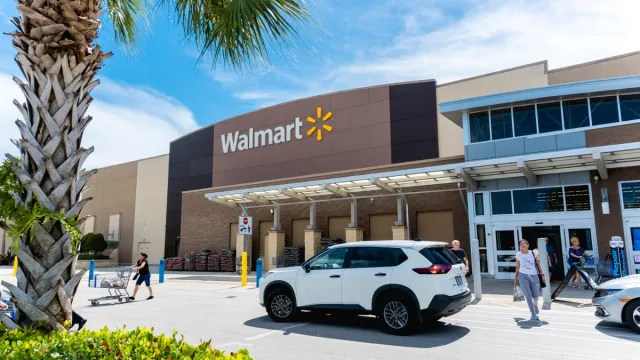 the outside of a Walmart store with customers walking out and a palm tree