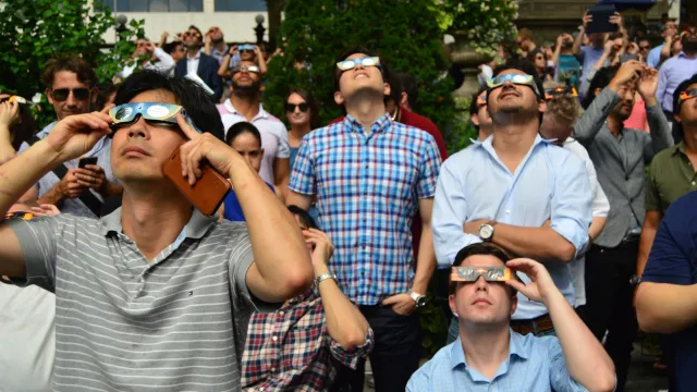 A crowd of people watching a solar eclipse with special safety glasses