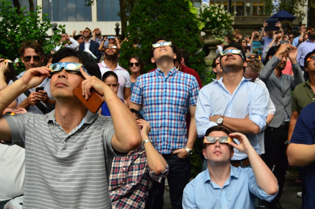 A crowd of people watching a solar eclipse with special safety glasses