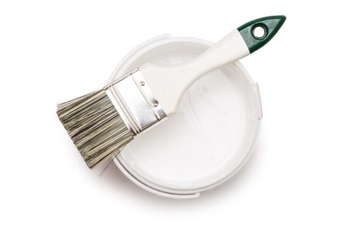 Open can of white paint with brush