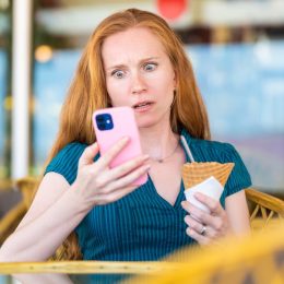 woman looking at her phone with a horrified expression