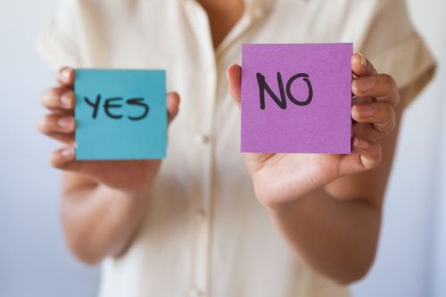 woman holding two post-it notes reading, "yes" and "no"
