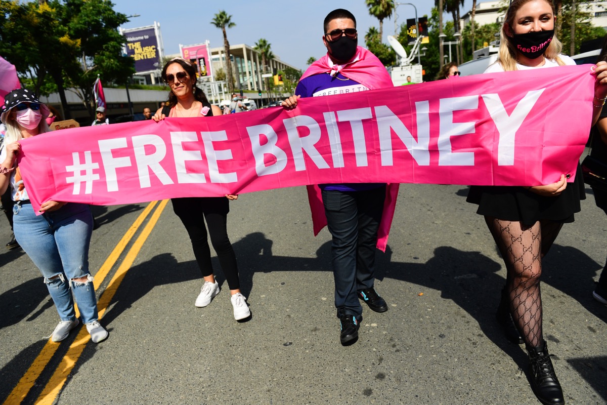 Four people walking with pink Free Britney banner at rally