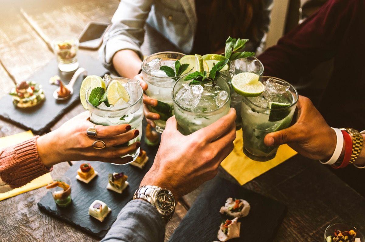 Close up of four people cheers-ing with mojitos