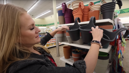 Kathryn Snearly holding up planters in Dollar Tree