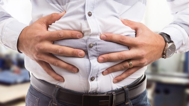 Man pressing grabbing bloated abdomen