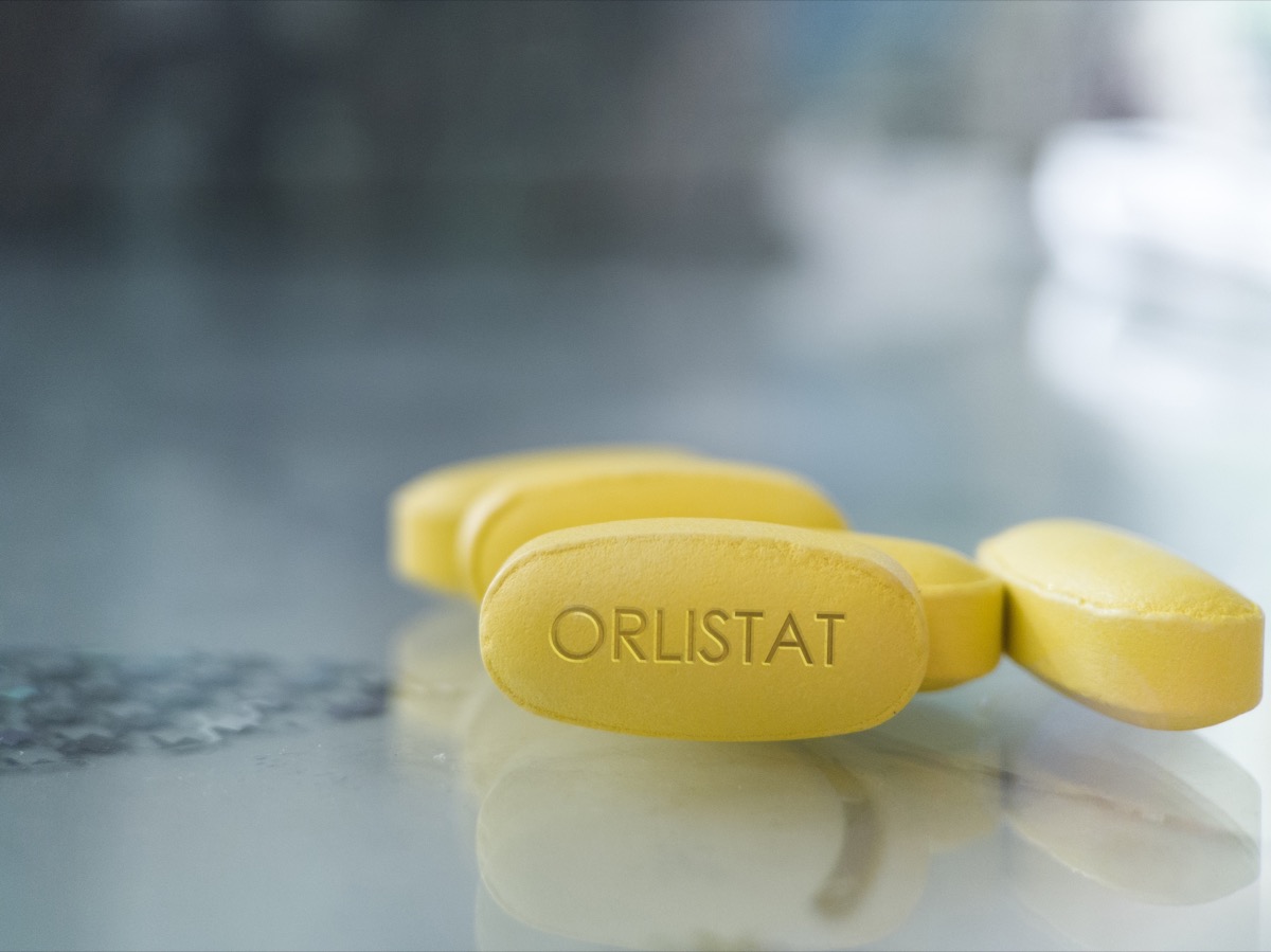 Orlistat yellow pill on glass background