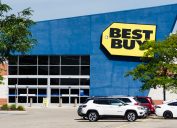 A Best Buy storefront with cars in the parking lot