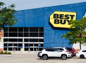 A Best Buy storefront with cars in the parking lot