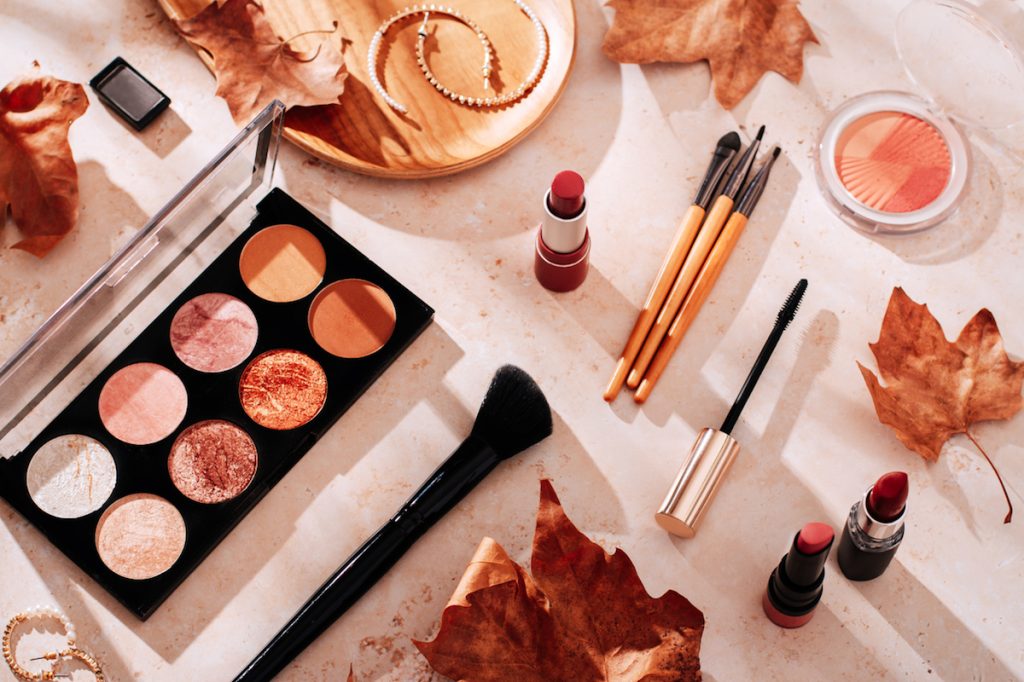 Beauty products and autumn leaves on beige background