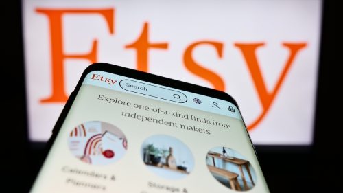 Etsy app on a phone with a large Etsy logo in the background