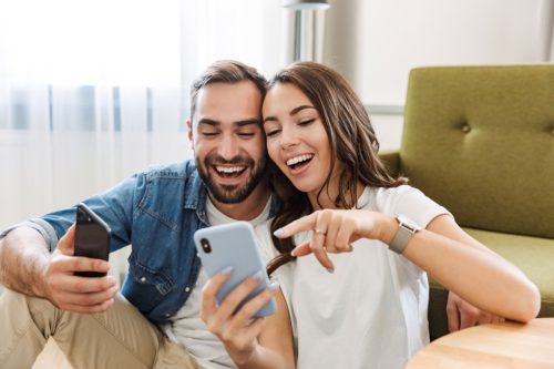 man and woman laughing at funny general knowledge questions on their phone