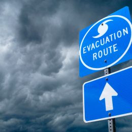 A close up of a hurricane evacuation route road sign with storm clouds in the background
