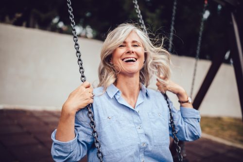 happy older woman with longer hair on swing