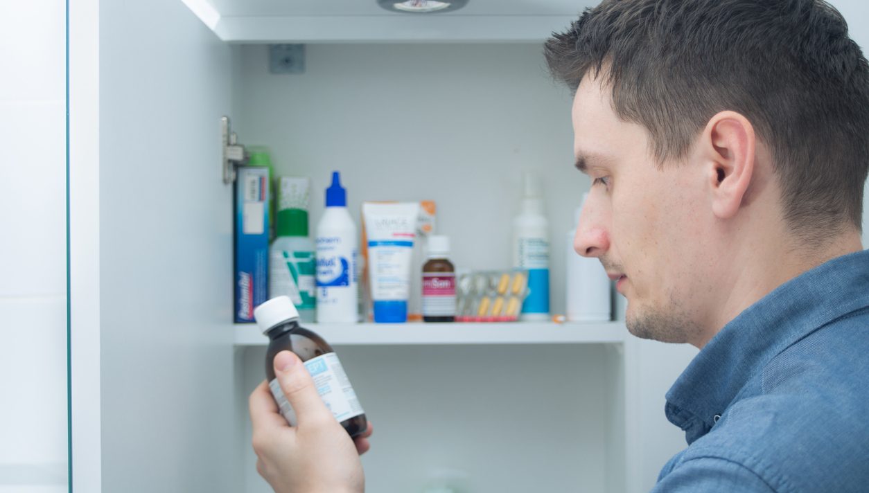 A person looking at a bottle of medicine from their medicine cabinet