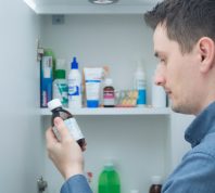 A person looking at a bottle of medicine from their medicine cabinet