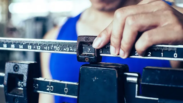 Sport man weighing himself on balance weight scale at the gym