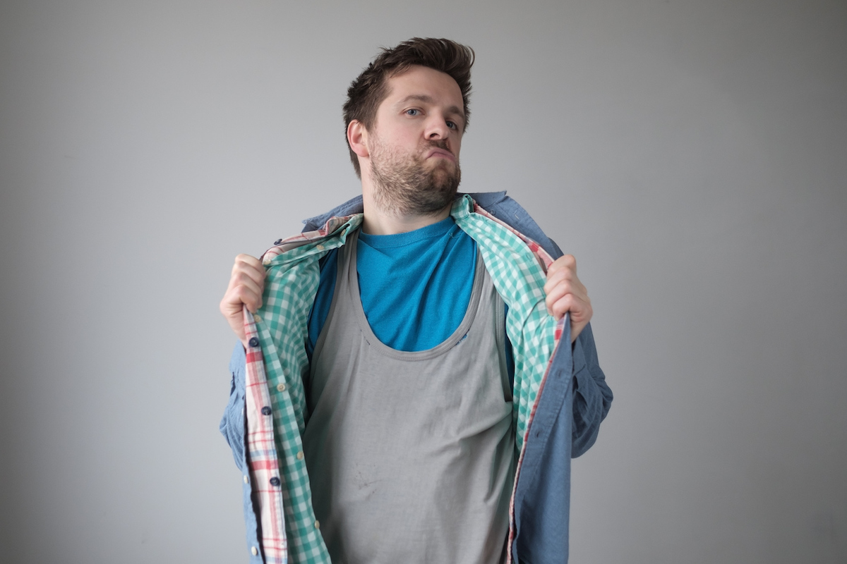 Man wearing multiple layers of shirts against a gray background