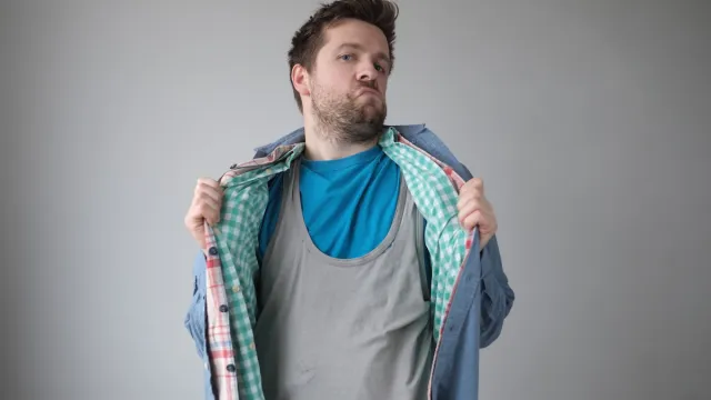 Man wearing multiple layers of shirts against a gray background
