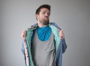 Man wearing multiple layers of shirts against a gray background
