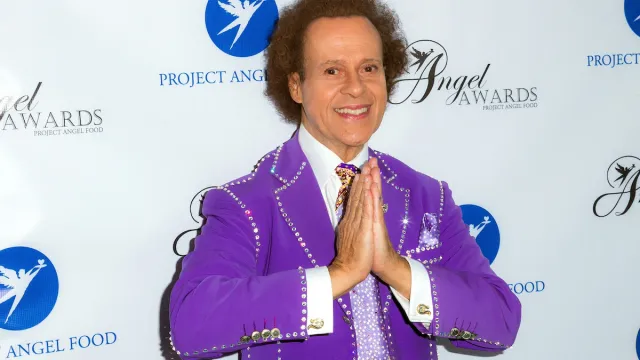 Richard Simmons posing in a purple suit