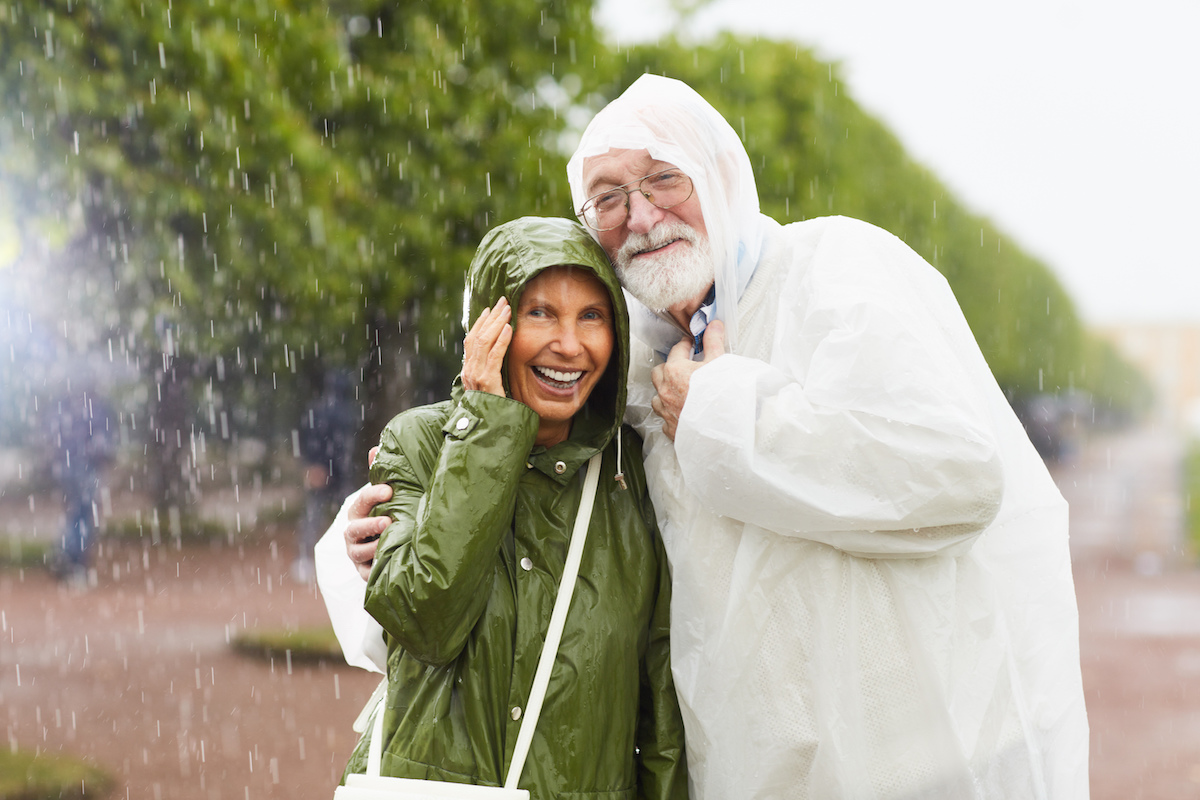 senior couple in raincoats laughing in the rain