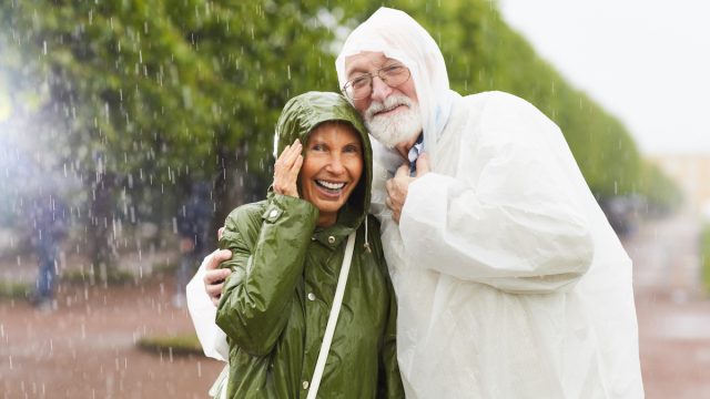 senior couple in raincoats laughing in the rain