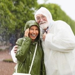 senior couple in raincoats laughing in the rain