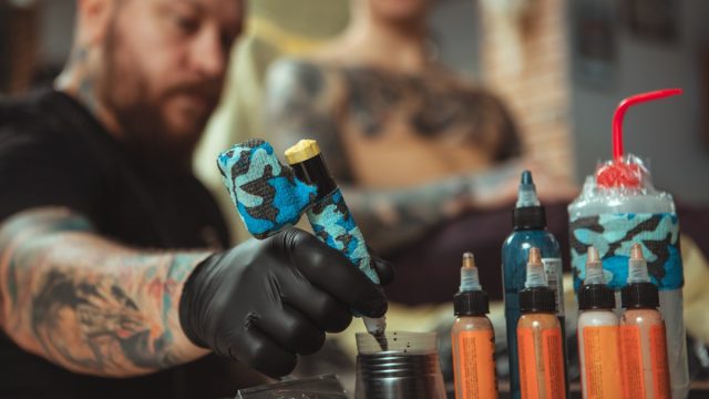 tattoo artist refilling pen with tattoo ink