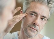middle-aged man looking at wrinkles in mirror