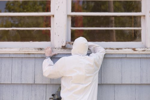 man scraping lead paint in hazmat suit