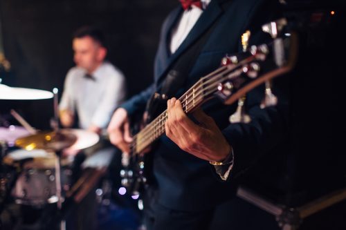 close up on a guitarist in a suit with drummer in the background