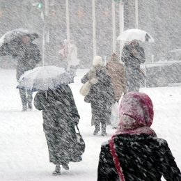 People walking in a snowstorm using umbrellas