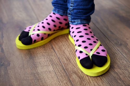 Close up of feet in pink and black polka dot socks with yellow flip flops