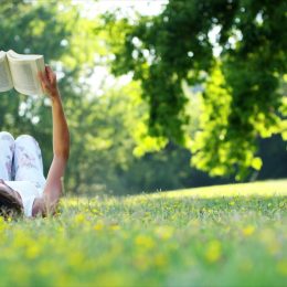 woman reading a book in the grass on a warm spring day