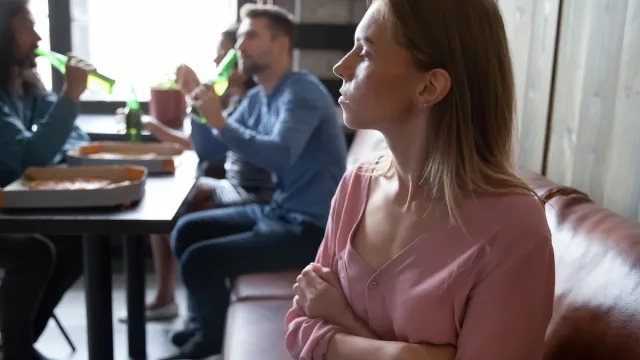 Upset offended young woman sitting separately from friends in cafe