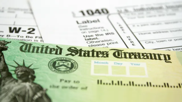A close up of a tax refund check next to a 1040 form and a W-2