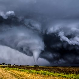 A tornado in a field surrounded by dark clouds