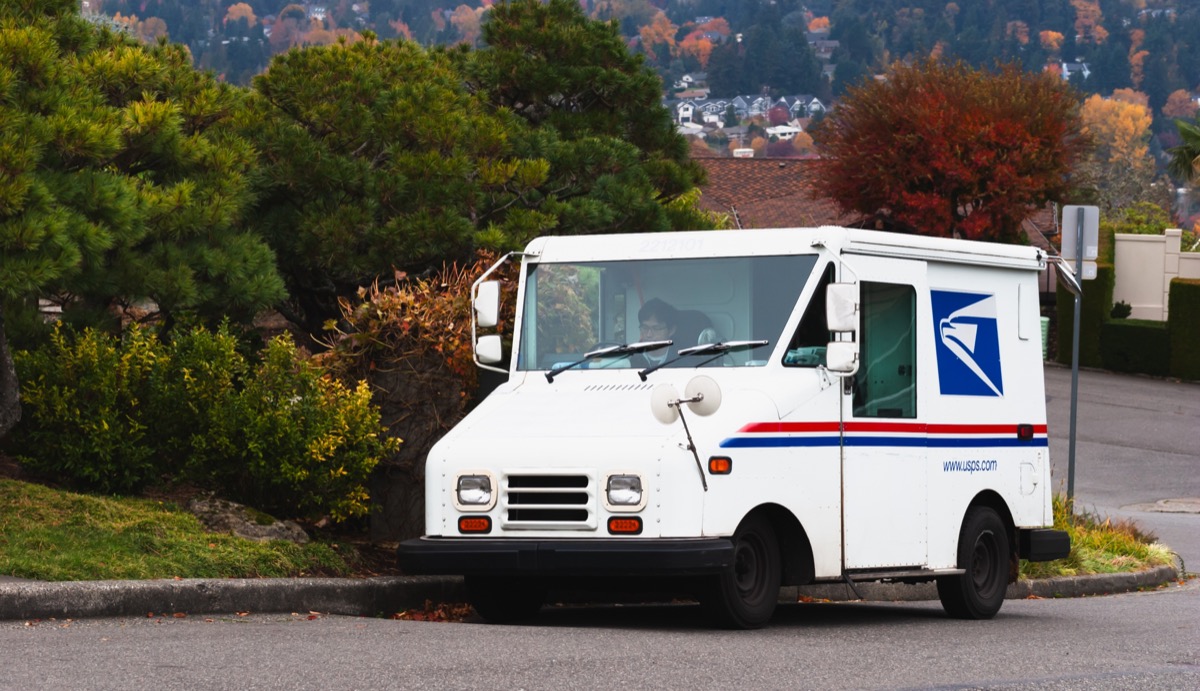 United States Postal Service USPS mail collection and delivery van in a neighborhood with a mailman. The USPS is responsible for providing postal service.